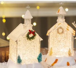 Close-up of lighted miniature Christmas church house with sparkling snow and LED glow