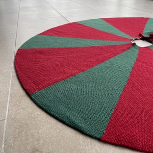Detail of red and green knitted Christmas tree skirt with festive radial patterns
