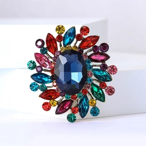 Detail of bohemian retro brooch featuring multi-color crystals and blue center stone