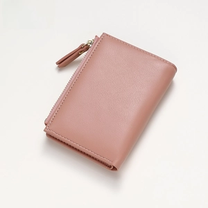 Close-up of dusty rose grain leather wallet showing fine stitching and gold zipper detail