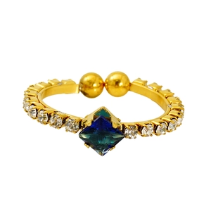 Detail of gold open ring featuring a square blue stone and side zircon accents