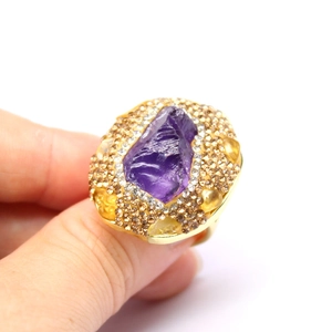 Close-up of vintage gold ring with raw purple amethyst and small pavé gemstones