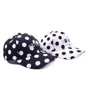 Detail of embroidered 'NATURAL' text on black and white polka dot baseball caps