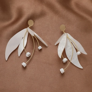 Detailed view of lily of the valley earrings on brown satin background with gold finish