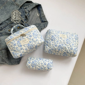 Close-up of three-piece blue floral quilted cotton makeup bags with brand labels