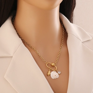 Gold stainless steel necklace with shell and heart charms on a model for close-up view
