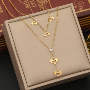 Close-up of golden layered heart necklace with gemstone pendant in a beige gift box