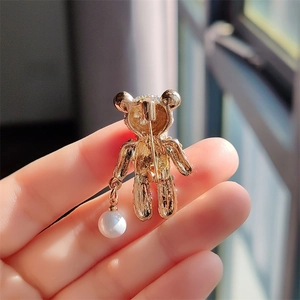 Detail of the golden metal bear brooch back showing the pin fastener and pearl charm