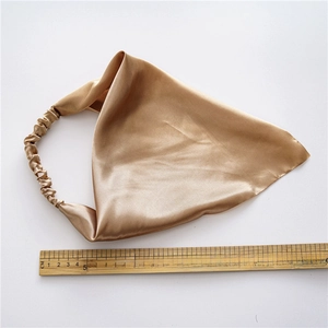 Macro detail of gold satin triangle headscarf showing 28cm size on wood ruler