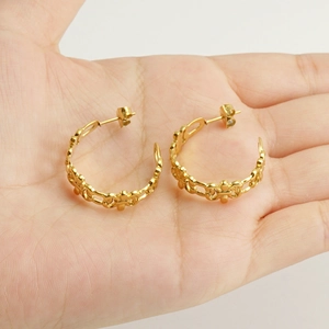 Vintage gold hollow-out C-shaped stainless steel earrings displayed on a hand