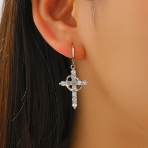 Detailed close-up of silver cross and crescent moon earrings with sparkling white zircons