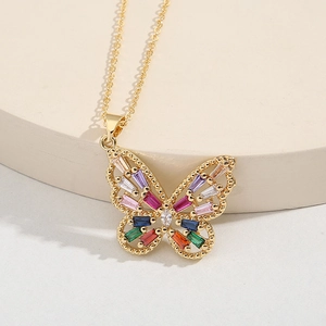 Collier pendentif papillon doré élégant avec pierres colorées sur support beige