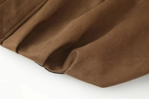 Detailed macro view of the soft brown suede texture and stitching on a bomber jacket