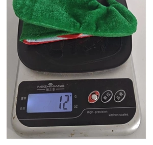 Close-up of a festive red and green Christmas stocking ornament weighing 12g on a scale