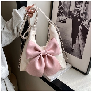 Detail of hobo bag featuring a large pink matte bow and polished white leather surface