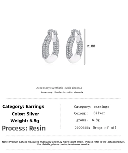 Detail view of silver donut earrings with cubic zirconia inlay and white oil drip finish
