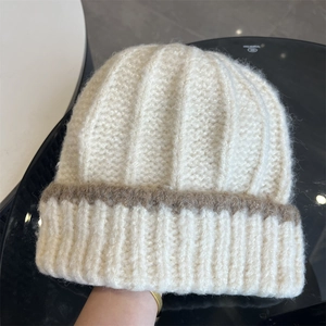 Détail de ce bonnet en maille crème avec texture cachemire douce et bande marron décorative