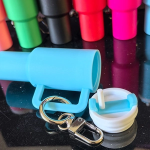 Close-up of sky blue mini tumbler keychain with lid and straw detail on a black surface