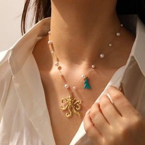 Dettaglio della collana d'oro con ciondolo a polpo, corallo turchese e piccole perle