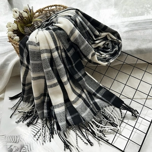 Classic black and white checkered cashmere-feel scarf with soft fringe on a woven basket