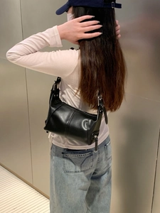 Detail view of the silver hardware and adjustable strap on this black leather shoulder bag