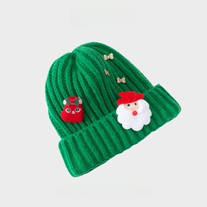 Detailed rib-knit texture of green Christmas beanie with Santa and bow ornaments