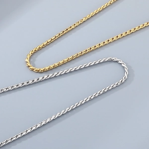 Close-up of gold and silver stainless steel twisted rope chains on a grey background
