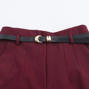 Detail of high waist pleated trousers with black belt and golden crescent moon buckle