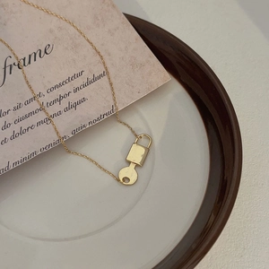 Close-up of golden 925 sterling silver padlock and key pendant with polished finish