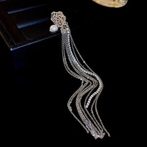 Silver long tassel earrings with rose and pearl details on a black leather jewelry box