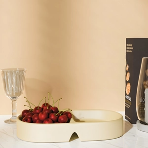 Detail of a beige oval double-compartment resin tray holding fresh red cherries