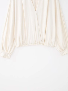 Détail de la blouse cache-cœur en satin montrant la texture et la coupe à la taille