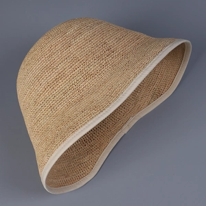 Close-up of woven raffia texture and cream fabric piping on the bucket sun hat brim