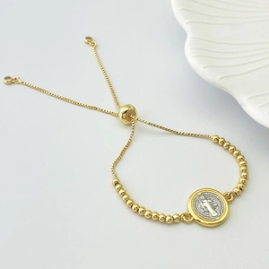 Detail of adjustable gold-plated Saint Benedict heart charm bracelet on white background