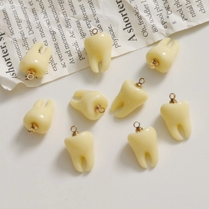 Set of 9 realistic 3D resin tooth pendants with gold rings on white aesthetic background