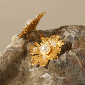 Macro shot of gold vintage flower earrings with pearls on a natural rock surface