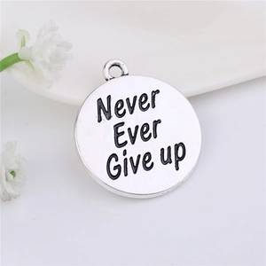 Detail of silver alloy pendant engraved with Never Ever Give Up quote on white background