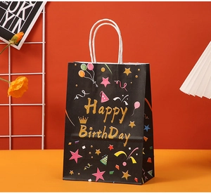 Detail of kraft paper gift bag with gold Happy Birthday text and colorful party patterns