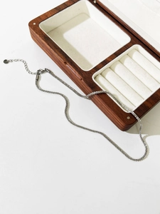 Macro shot of silver titanium necklace chain with lobster clasp and wooden jewelry box