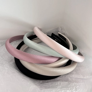 Detail of colorful satin headbands stacked on white paper showing handmade labels