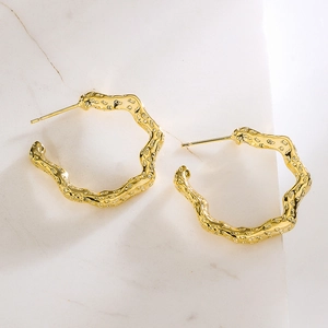 Gold plated twisted C-shaped hoop earrings with textured finish and irregular design