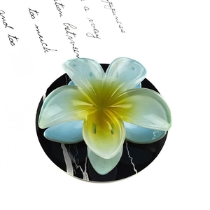 Macro shot of translucent blue frangipani flower hair claw on marble tray detail