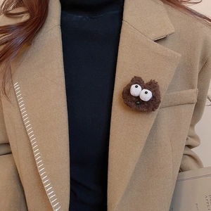 Brown plush cartoon monster brooch styled on a khaki wool blazer lapel for winter
