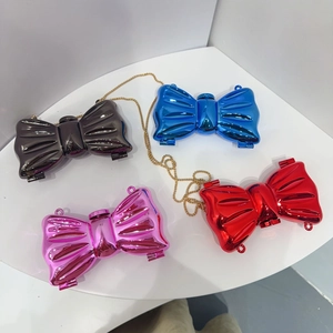 Mini acrylic evening bags in bow shape featuring metallic finish and golden chains