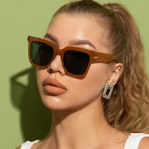 Close-up of square oversized amber sunglasses with translucent frames on a model