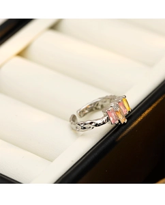 Macro shot of silver irregular ring with pink and yellow gemstones in a jewelry box