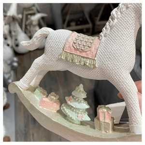 Detail of white resin rocking horse ornament with pink saddle and miniature gift boxes