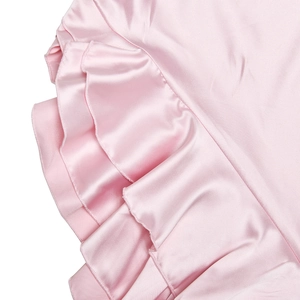Detail of pink satin dress featuring elegant tiered ruffles and smooth silk texture