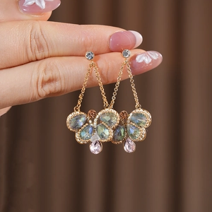Close-up of vintage butterfly drop earrings with colorful crystals in antique gold finish