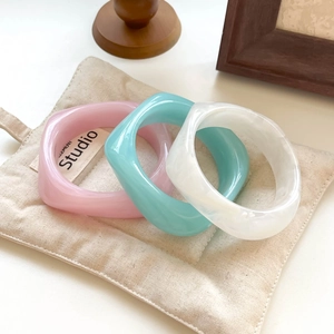 Close-up of resin marble pattern bangles in pink and blue colors on a canvas bag